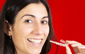 Woman holding Invisalign in Milton on red background