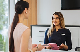 Woman checking in at dental office reception desk