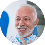 man smiling while holding dental mirror 