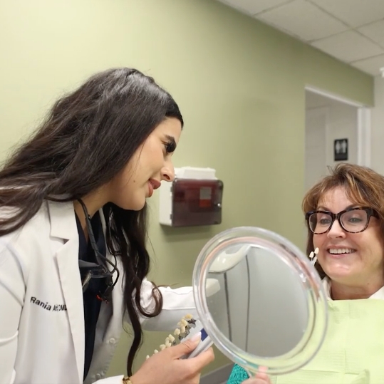 doctor holding mirror for patient