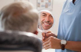 Man looking at smile after metal free dental restoration