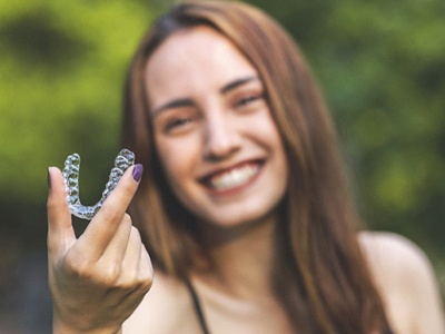 Woman holding Invisalign in Milton
