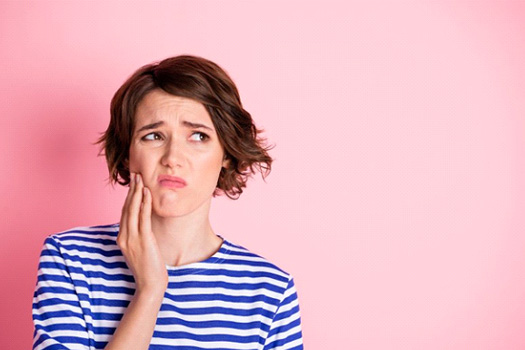 Woman rubbing her jaw and looking miserable