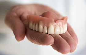 Hand holding full dentures