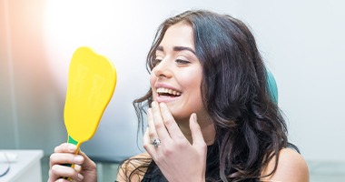 Woman looking at her smile after cosmetic dentistry