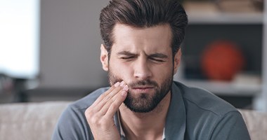 Man in need of emergency dentistry holding cheek