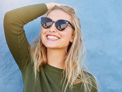 woman in sunglasses smiling after getting teeth whitening in Milton