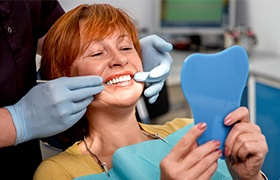 Woman looking at her smile after porcelain veneer placement