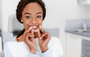 Woman in dentist’s chair holding a clear aligner