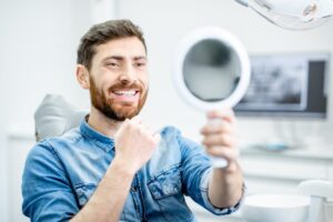 smiling dental patient looking in a handheld mirror