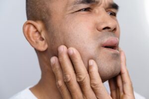 Man with swollen face holding his jaw.